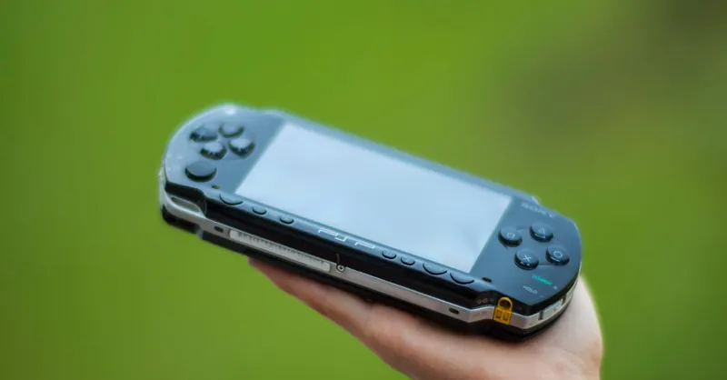 A hand holding a portable gaming console against a vibrant green background, showcasing modern technology.