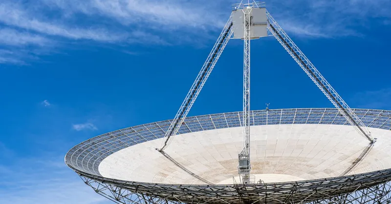 A large satellite dish with a clear blue sky in the background, showcasing modern communication technology.