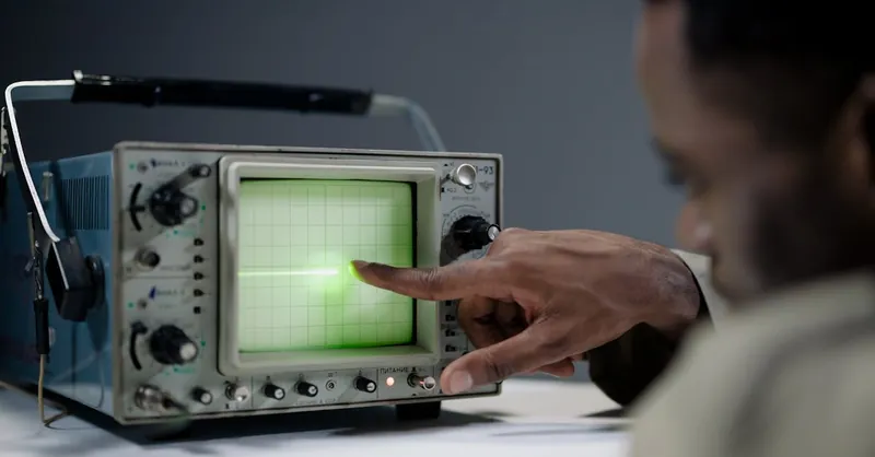 Close-up of a person pointing at a vintage oscilloscope screen in a tech setting.