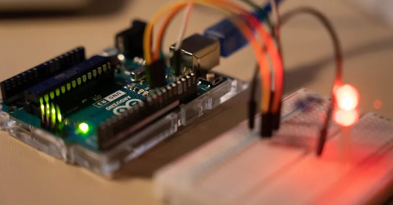 Close-up of Arduino microcontroller connected to a breadboard with a glowing LED.