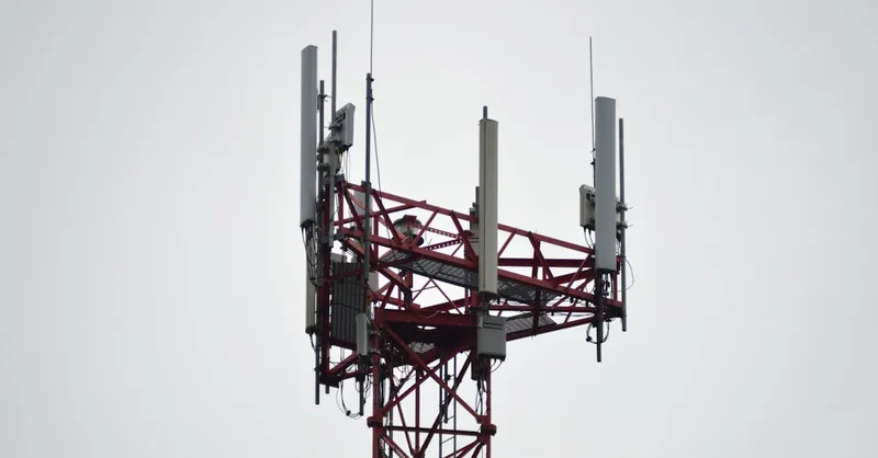 A red communication tower with antennas stands tall against a gray sky.