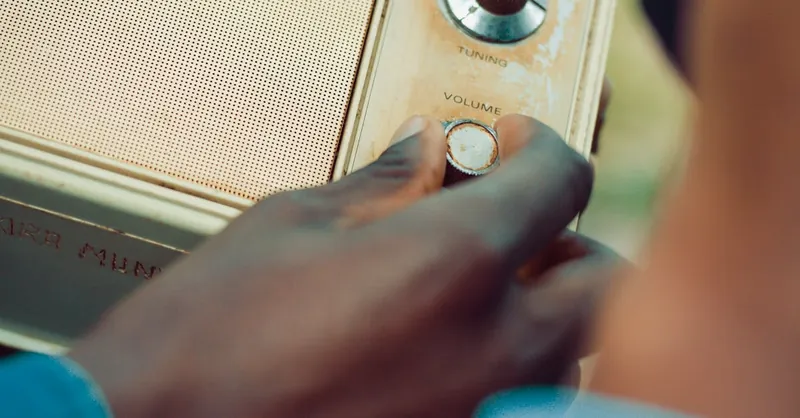 Hand adjusting volume on a vintage radio in an outdoor setting.